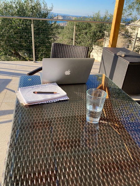 Tisch auf Terrasse mit Notebook Notizblock Stift und Wasserglas