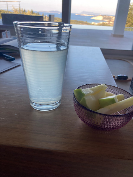 Glas mit Zitronenwasser und kleine Schale mit aufgeschnittenen Äpfeln auf einem Tisch